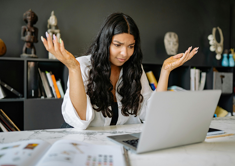 woman using a laptop while shrugging