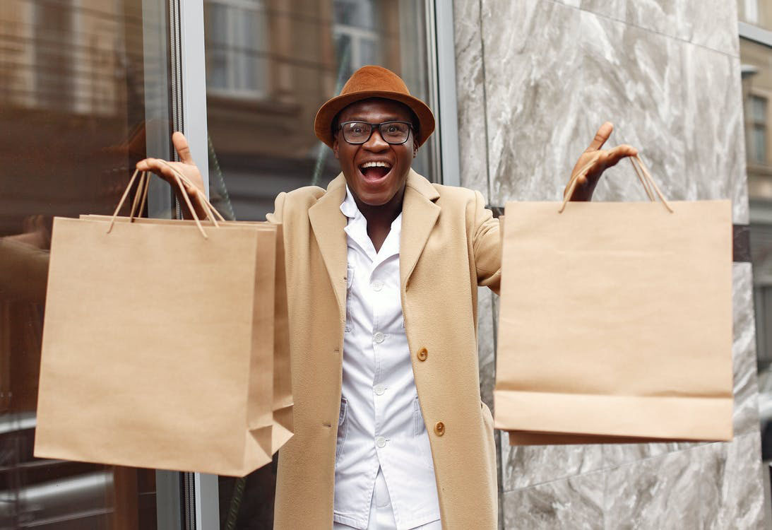 happy man holding two brown shopping bags