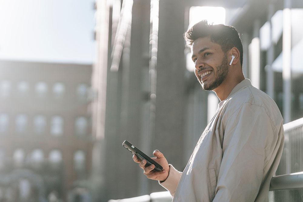 happy man with airpods in his ears and holding his phone