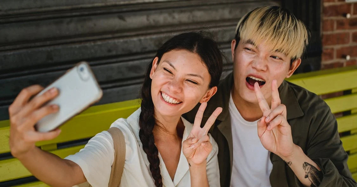 a girl taking a selfie with a boy while they both holding up peace signs