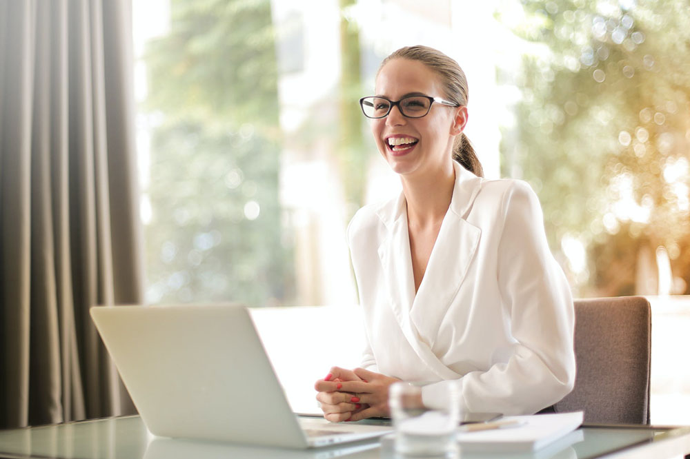 laughing businesswoman sitting in front of a laptop