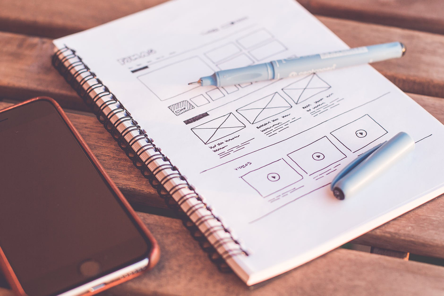 website design outline drawn in a notebook with a phone sitting next to it