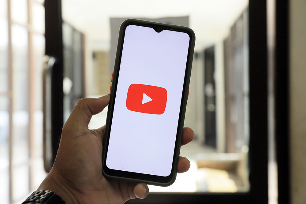 someone holding a phone with the youtube app opening