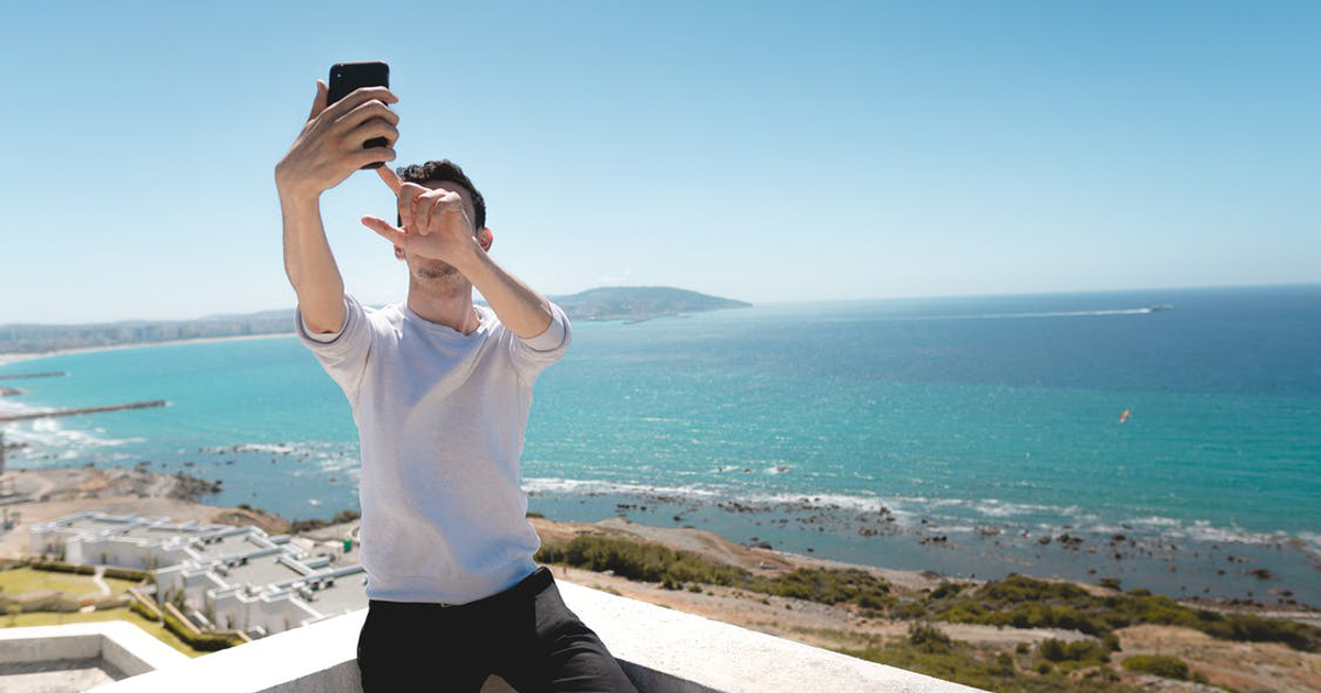 a man taing a selfie of himself standing on a balcony that overlooks the ocean