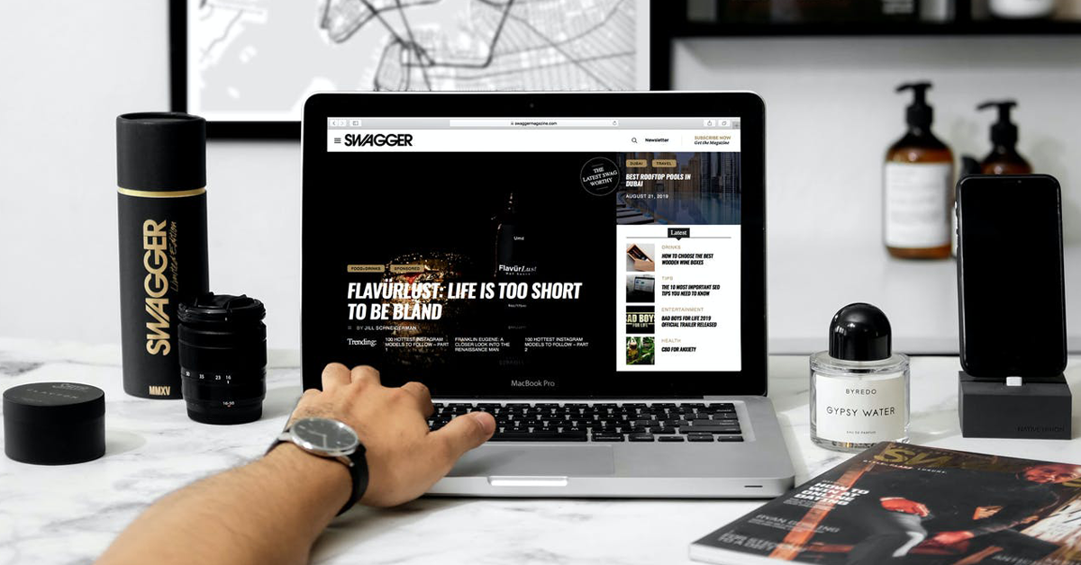 laptop open to a site called Swagger with Swagger-branded items placed next to it