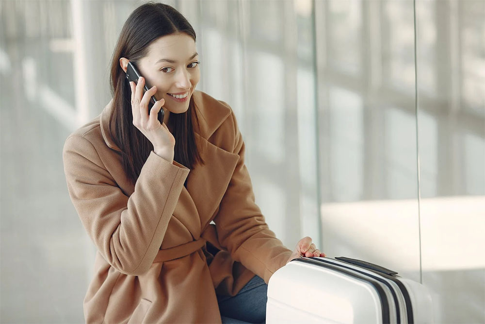 Charming woman talking on smartphone in airport<br /> 