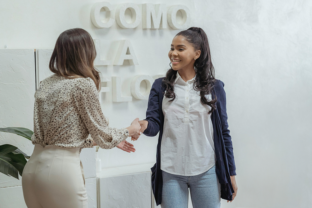 smiling woman greeting woman in office