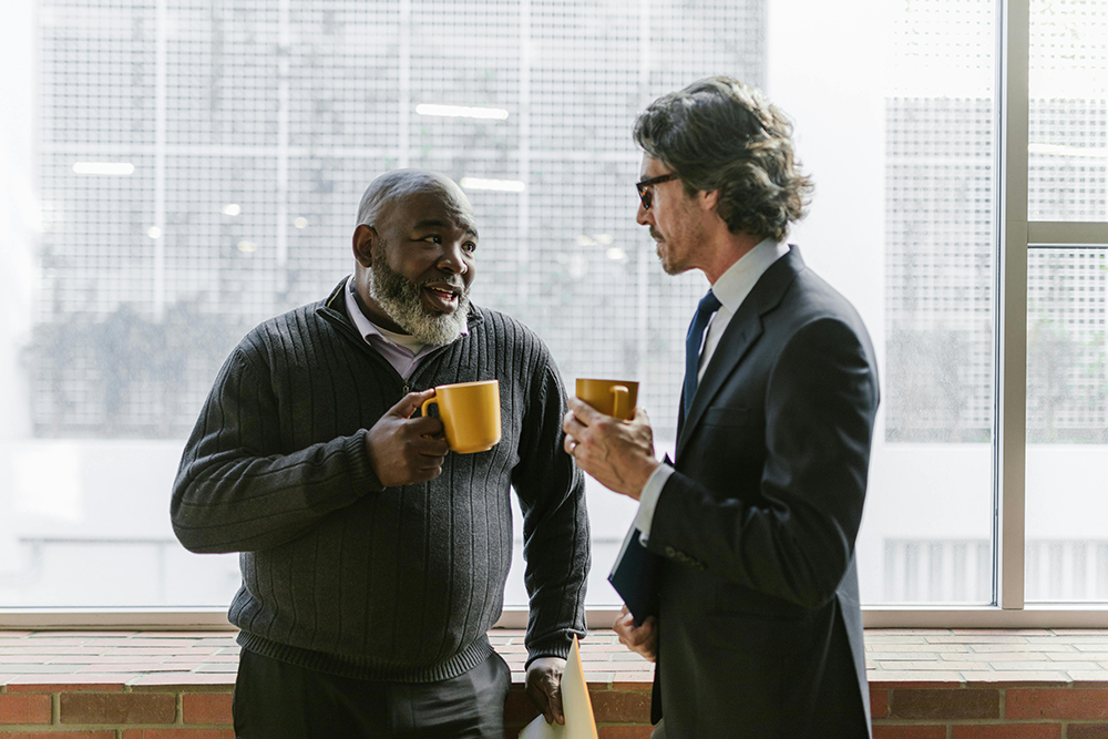 two business men talking and holding mugs