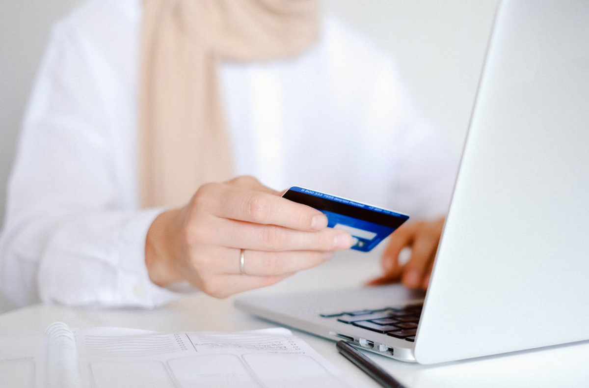 a woman at her laptop while holding a credit card