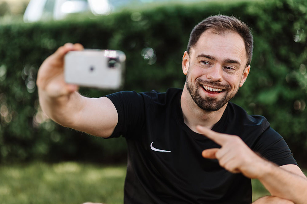 a man taking a selfie with his phone while wearing a black nike shirt