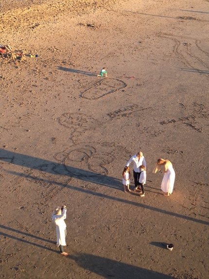 砂浜に絵を描いてる家族
